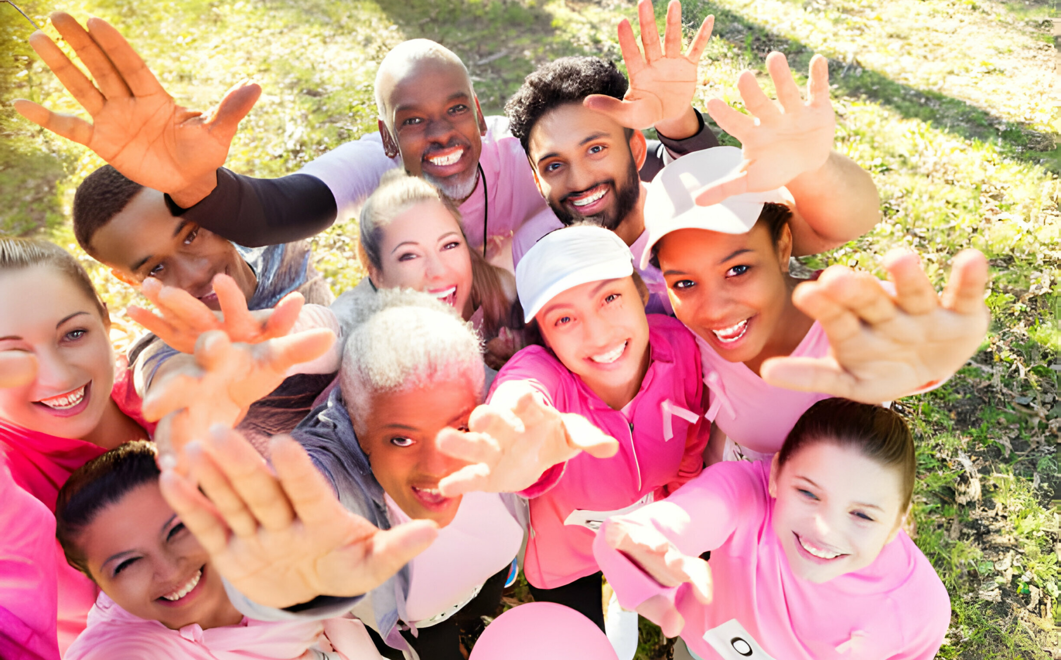 A group of youths wearing pink attire reaching their hands towards the camera.