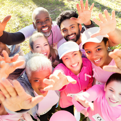 A group of youths wearing pink attire reaching their hands towards the camera.